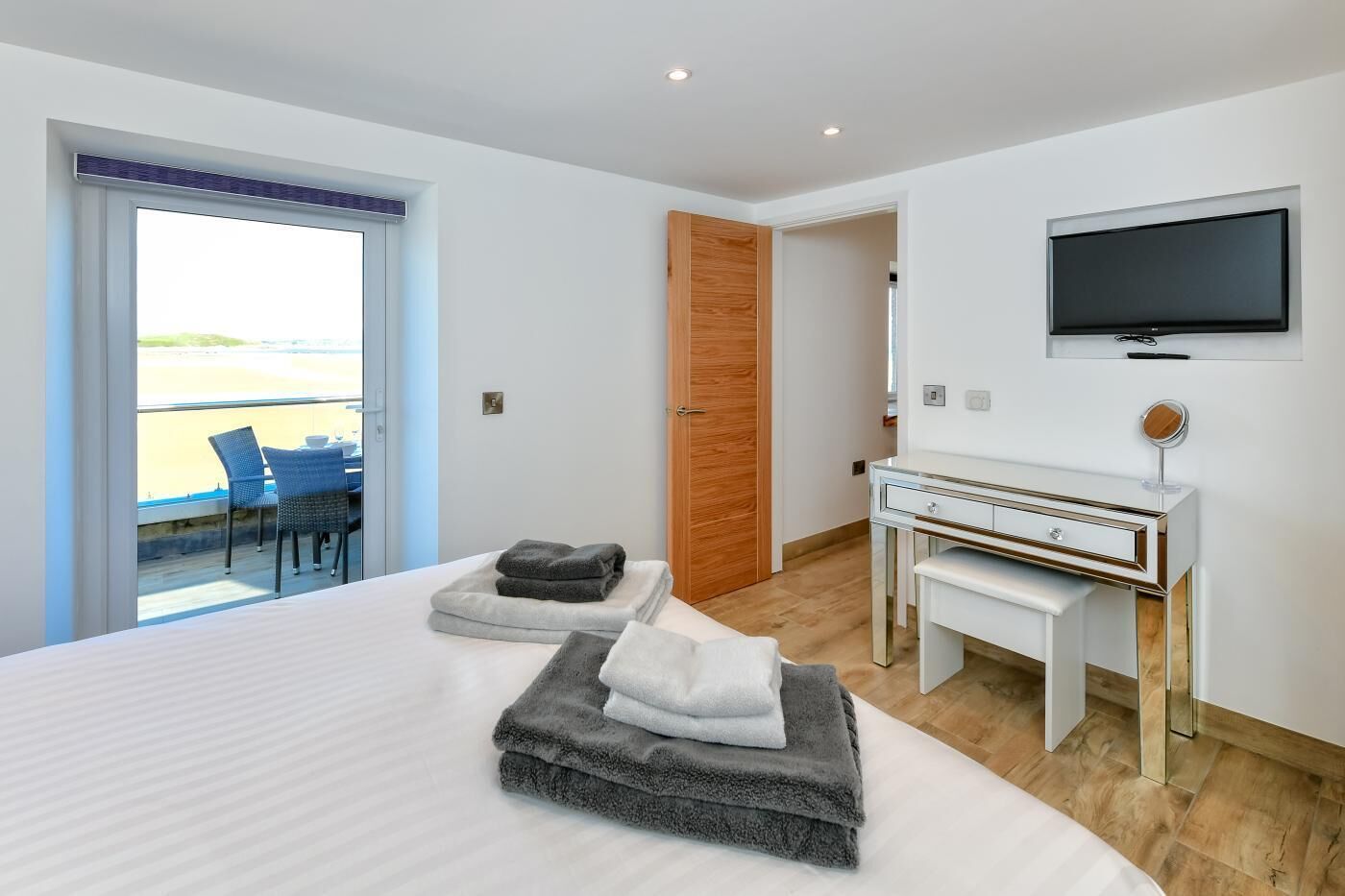 A modern hotel room with a large bed, a desk, and a TV.