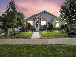A two-story house with a front porch, a driveway, and a well-maintained lawn. - Cozy & Comfy Mountain-View Home Airport 15 min (West Valley City)
