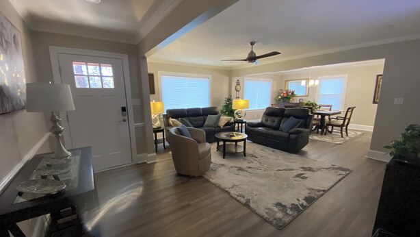 A spacious living room with a fireplace, a dining area, and a kitchen in the background. - Peaceful 3BR NW Raleigh Ranch Home. Pet friendly, RDU, UNC/Rex, Crabtree Mall (Raleigh)