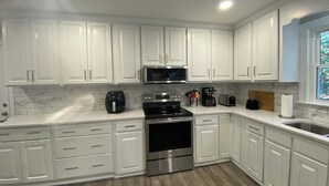A modern kitchen with white cabinets, a stainless steel oven, a microwave, and a coffee maker. - Peaceful 3BR NW Raleigh Ranch Home. Pet friendly, RDU, UNC/Rex, Crabtree Mall (Raleigh)