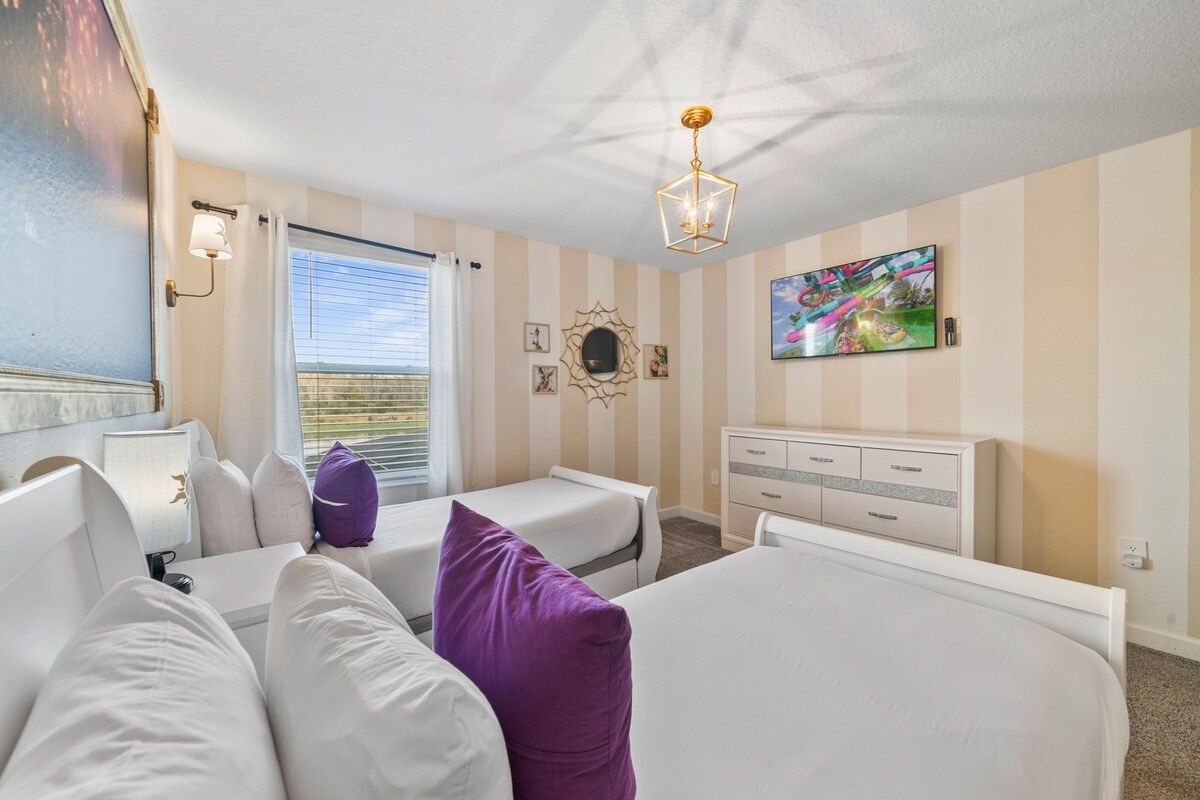 A hotel room with two beds, a desk, a chair, a TV, and a window with curtains.
