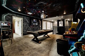 A pool table in a room with a space-themed ceiling, a television, and a Midway arcade machine. - *Arcade Games*Theme Rooms*Pvt Pool*Cinema Seats* (Kissimmee)