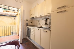 A compact kitchen with beige cabinets, a built-in oven, and a sink. - San Niccolò Elegant Apartment (Florence)