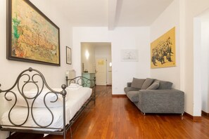 A bedroom with a metal bed frame, a gray sofa, and two paintings on the walls. - San Niccolò Elegant Apartment (Florence)