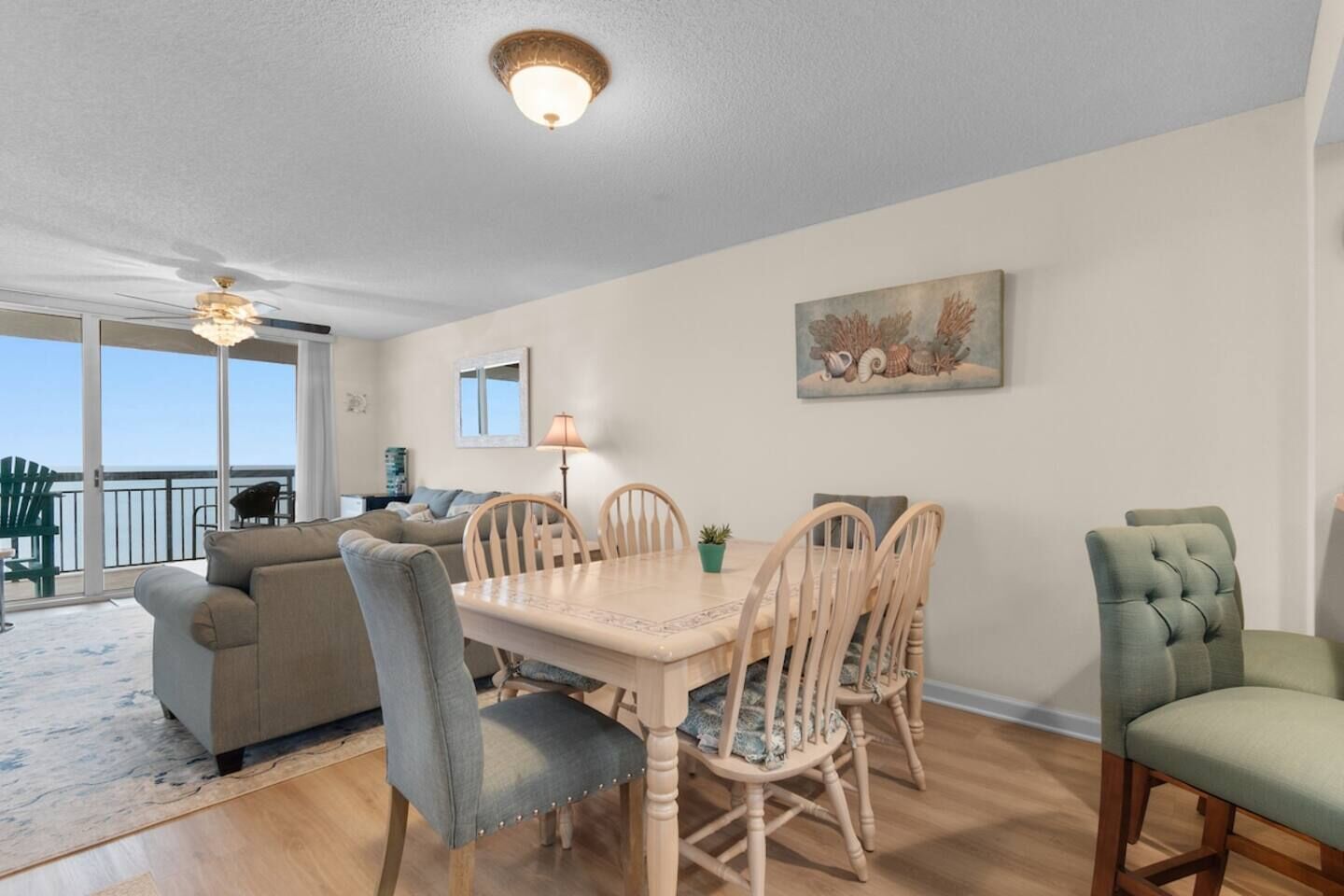 A dining area with a table, chairs, a ceiling fan, and a view of the outdoors.