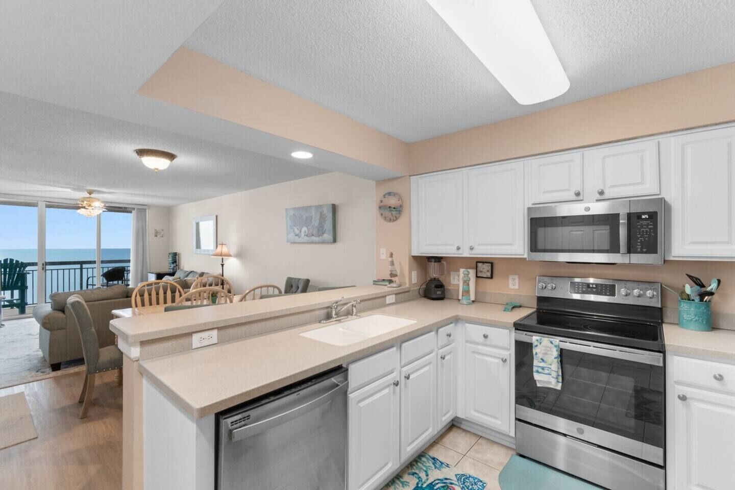 A modern kitchen with white cabinets, stainless steel appliances, and a view to the outside.