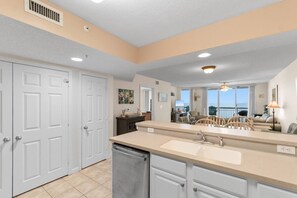 A kitchen with a double sink, white cabinets, and a view of the living area. - 3 Bdrm North Shore Villa w/ Lazy River, Hot Tub (North Myrtle Beach)