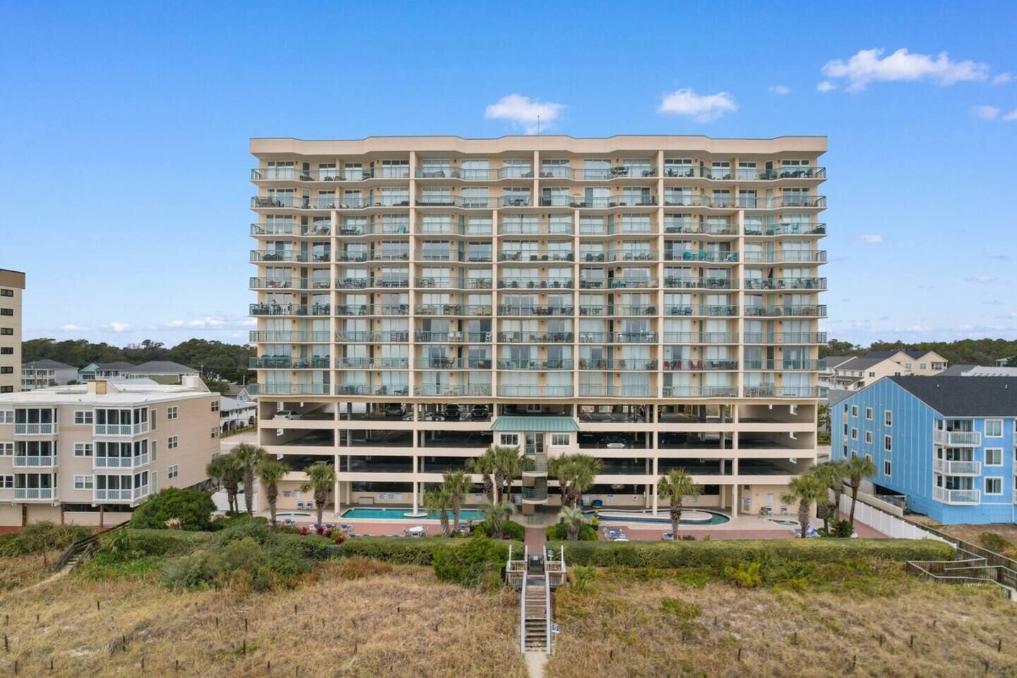A multi-story hotel with a pool area and a view of the surrounding landscape.
