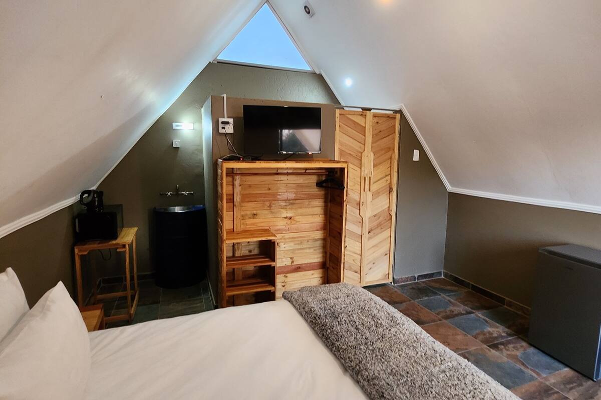 Un dormitorio con cama, armario de madera, televisor y una lámpara en el techo.