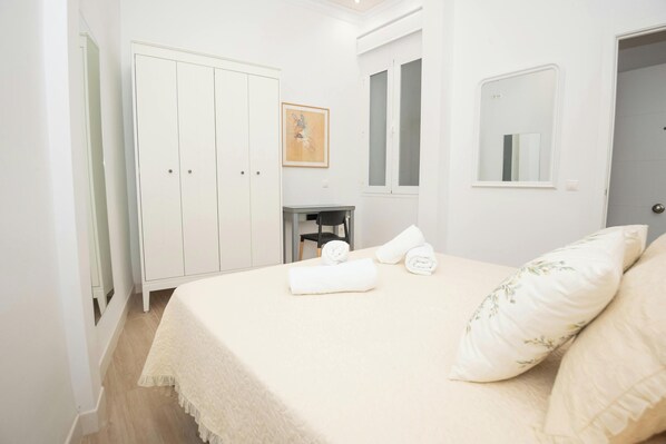 A bedroom with a bed, a wardrobe, a chair, and a small table.