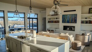Una cucina moderna con un'isola grande, scaffali a incasso e vista sulle montagne.