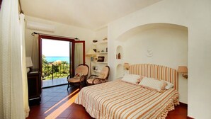 A bedroom with a large bed, a chair, a desk, and a view of the ocean. - Villa Faraglioni – Private Beach in Cefalù (Cefalù)