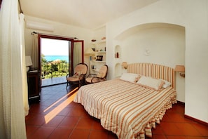 A bedroom with a large bed, a chair, a desk, and a view of the ocean. - Villa Faraglioni – Private Beach in Cefalù (Cefalù)