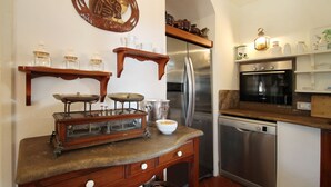 A kitchen with a vintage scale, stainless steel appliances, and wooden shelves. - Villa Faraglioni – Private Beach in Cefalù (Cefalù)