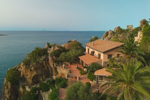 A coastal property with a stone pathway leading to a building with a tiled roof, surrounded by lush greenery and overlooking the sea. - Villa Faraglioni – Private Beach in Cefalù (Cefalù)