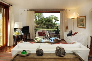 A living room with a sofa, a coffee table, a TV, and a view of the outdoors.