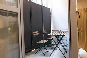 A small outdoor seating area with a table and chairs, enclosed by a glass door and a metal partition. - Santa Croce Loft - Florence (Firenze)