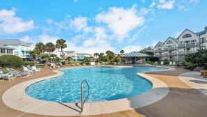 A swimming pool with a metal ladder, surrounded by lounge chairs and a poolside area with a curved edge. - 🐬GS Plantation Resort Conference Center 1254 | Resort Amenities+Walk to Beach (Gulf Shores)