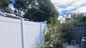 Um pátio pavimentado com vasos de plantas e um cercado branco.