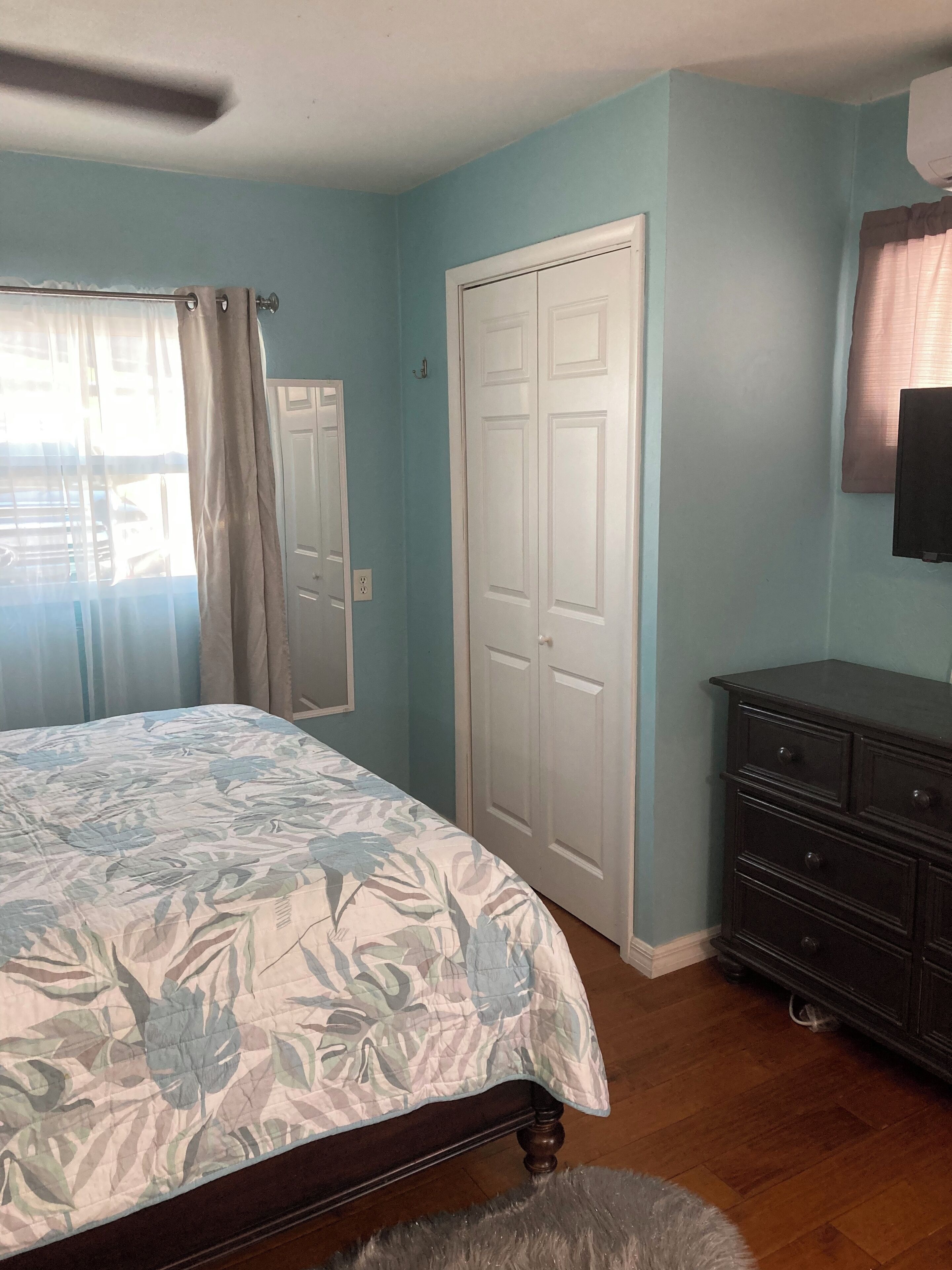A bedroom with a bed, a wardrobe, a dresser, and a ceiling fan.