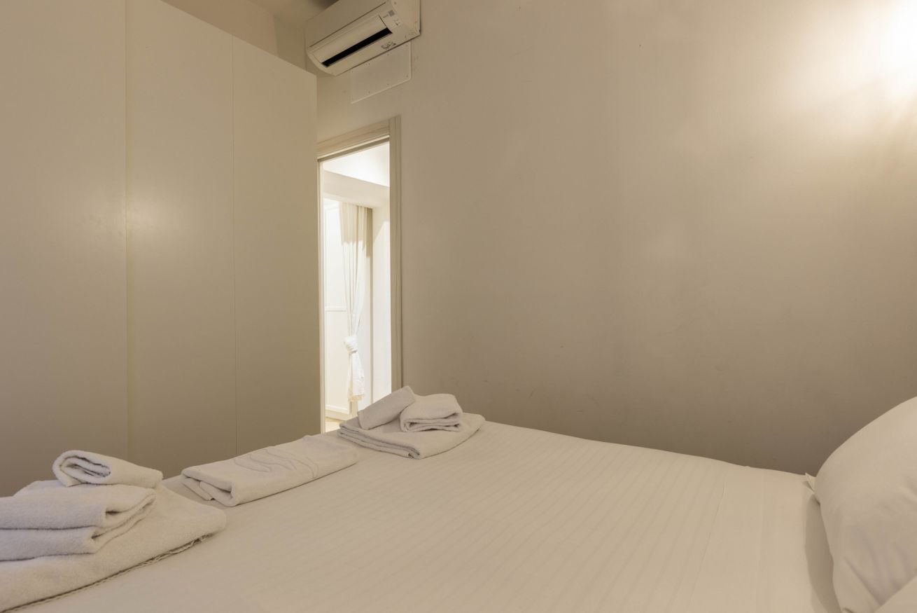 A hotel room with a bed, a bathroom door, and a window.