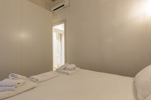 Hotellihuone, jossa on sänky, kylpyhuoneen ovi ja ikkuna.