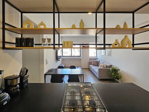 Eine moderne Küche mit Gasherd, Kaffeemaschine und Regalen mit Küchenutensilien.