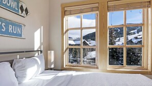 Une chambre avec une grande fenêtre, un lit et deux panneaux accrochés au mur.