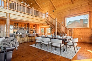 Eine geräumige Holzhütte mit Essbereich, Küche und einer Treppe zu einem Erkerzimmer.