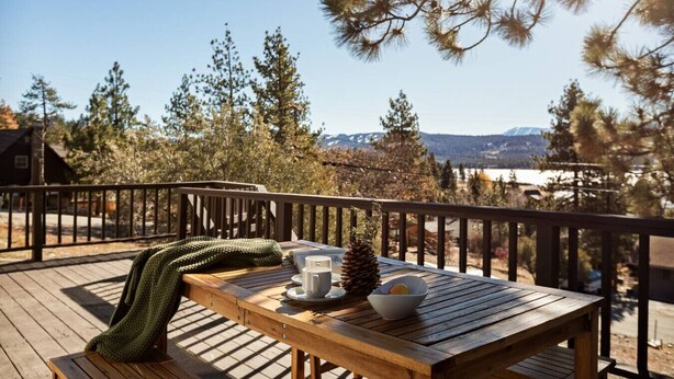 Una terrazza in legno con un tavolo apparecchiato per un pasto, con vista su un paesaggio montuoso.