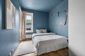 A bedroom with a large bed, a window with curtains, and a view of buildings outside. - City Lux Stay in Oslo (Oslo)