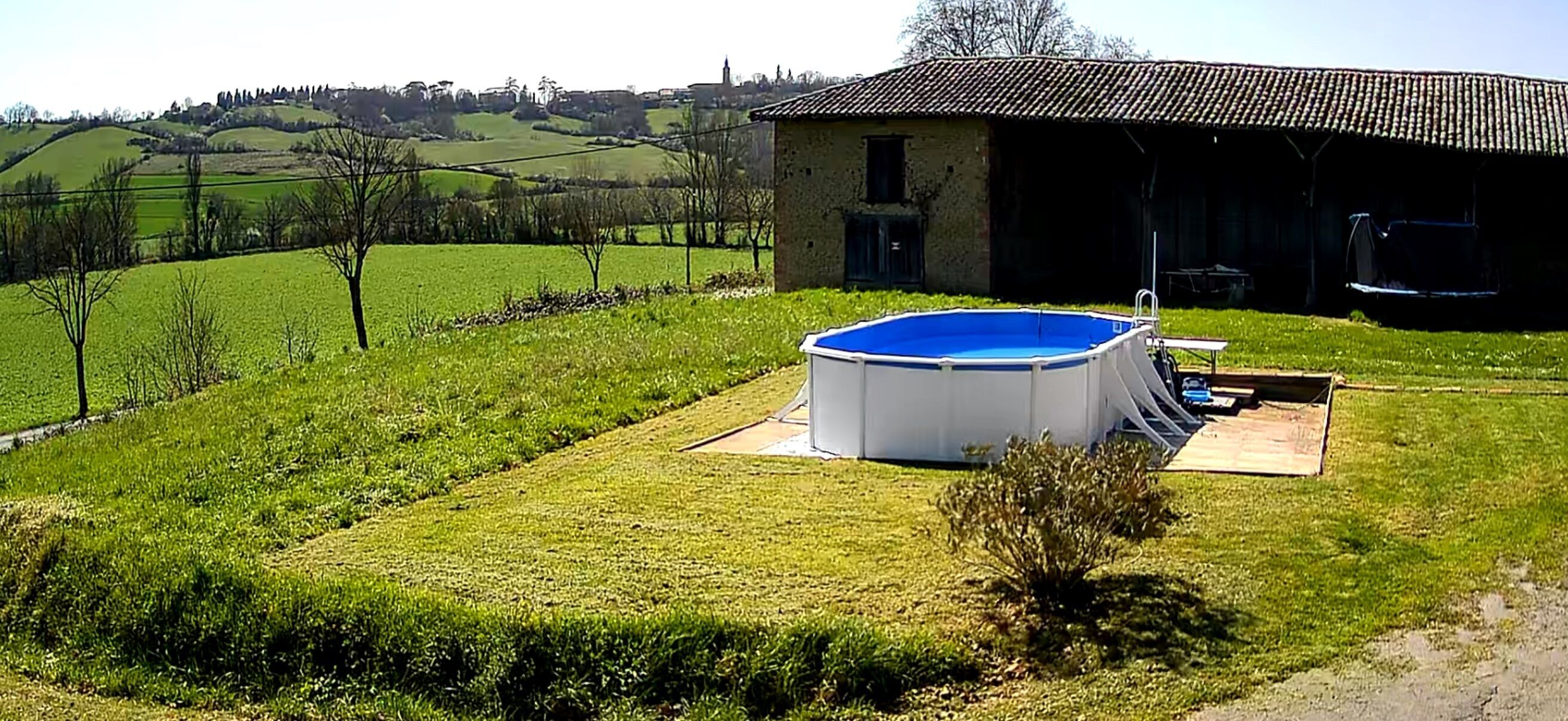 A swimming pool in a grassy area with a building in the background.