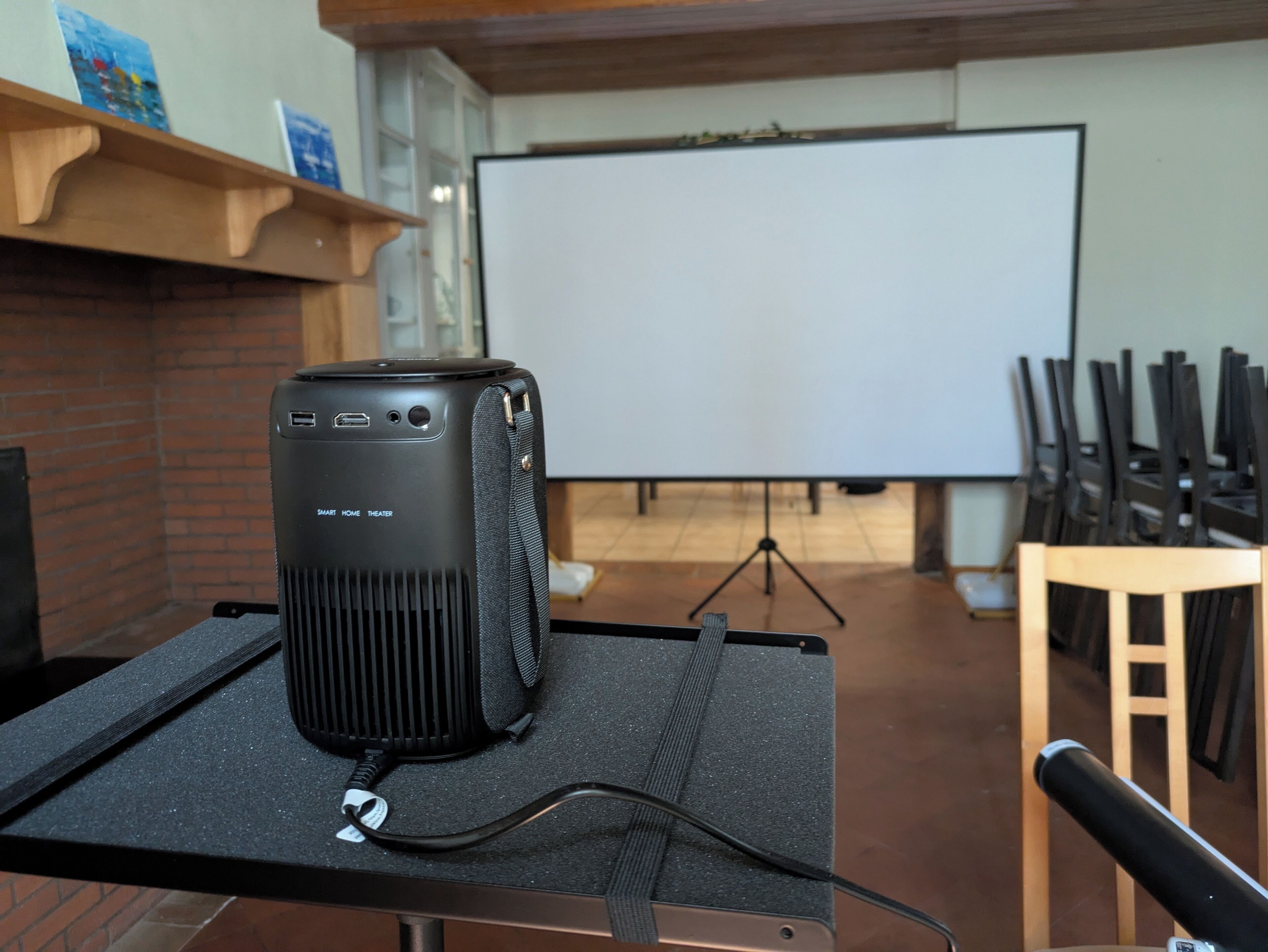 Un proyector sobre una mesa con una pantalla en blanco al fondo.