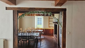 Un espace repas avec une longue table et des chaises, une fenêtre avec des rideaux et un plafond en bois.