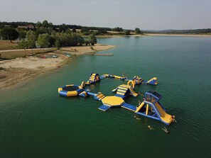 Un parc aquatique en plein air doté de structures de jeux gonflables et d’une zone de plage de sable.