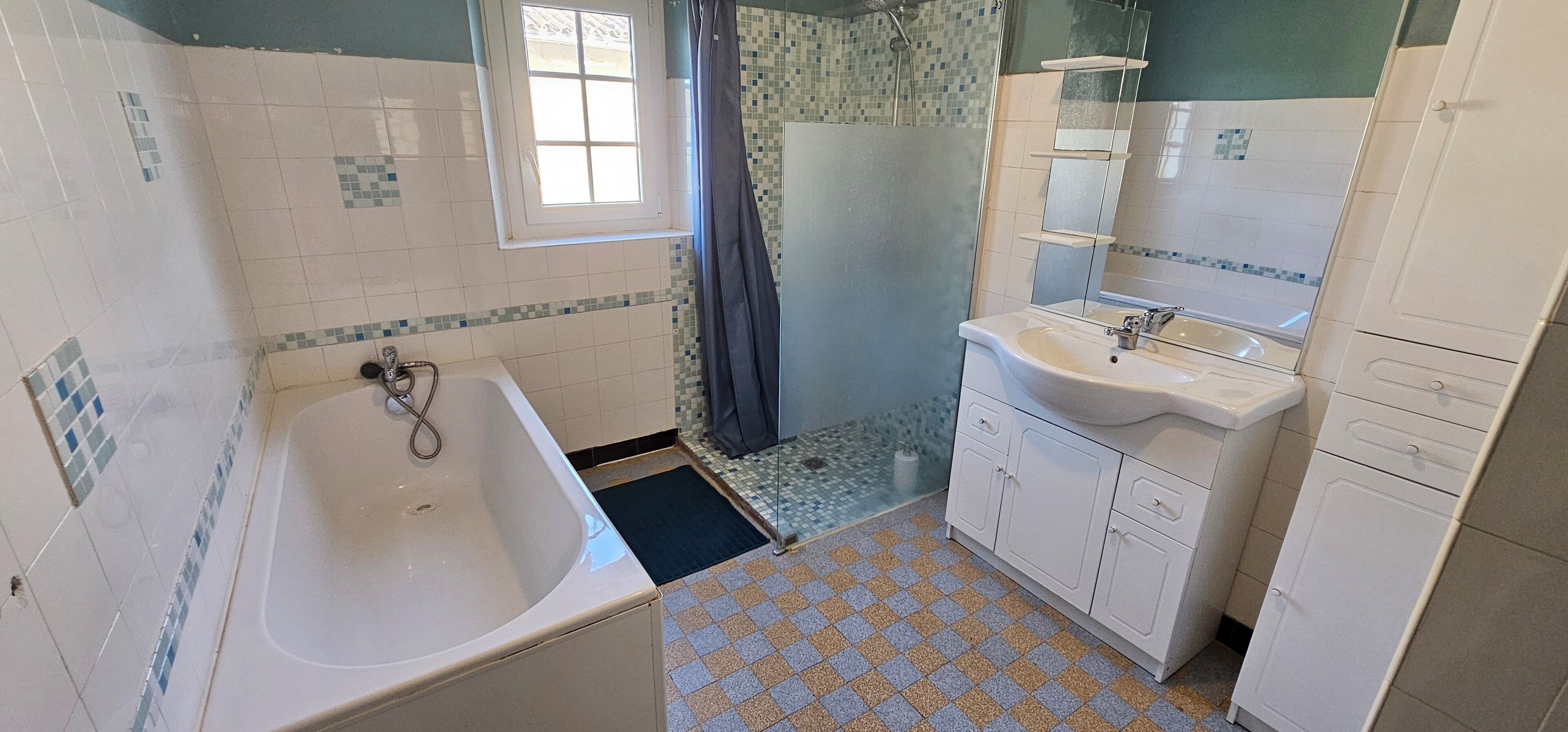 A bathroom with a bathtub, a sink, and a shower area.