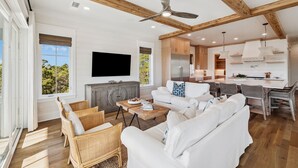 A spacious living room with a white sofa, wicker chairs, a wooden coffee table, and a ceiling fan. - Crabstar|Easy Beach Access|Private Pool & Golf Cart (Inlet Beach)