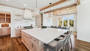 A spacious kitchen with a large island, wooden beams, and pendant lighting. - Crabstar|Easy Beach Access|Private Pool & Golf Cart (Inlet Beach)