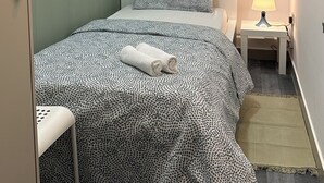 Ein Schlafzimmer mit einem Bett, einem Nachttisch, einer Lampe, einer Uhr und einem gerahmten Bild an der Wand.