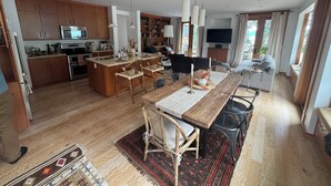 Una cocina moderna con armarios de madera, una isla central y un comedor con mesa y sillas de madera.
