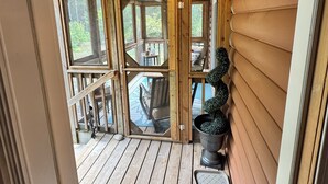 A wooden deck with a glass door leading to a patio area. - Spacious Luxe-Lodge 5br Lakefront (Greenfield)
