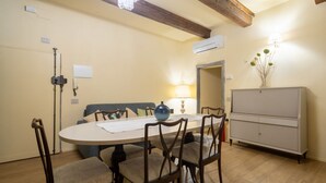 Een eetgedeelte met een ronde tafel, stoelen, een bank en een kast.