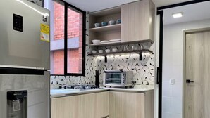 Una cocina moderna con microondas integrado, dispensador de agua y estufa a gas.