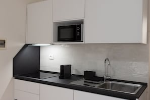 A modern kitchen with a black countertop, stainless steel sink, and a built-in microwave. - Bargello Apartment - Florence City Center  (Firenze)