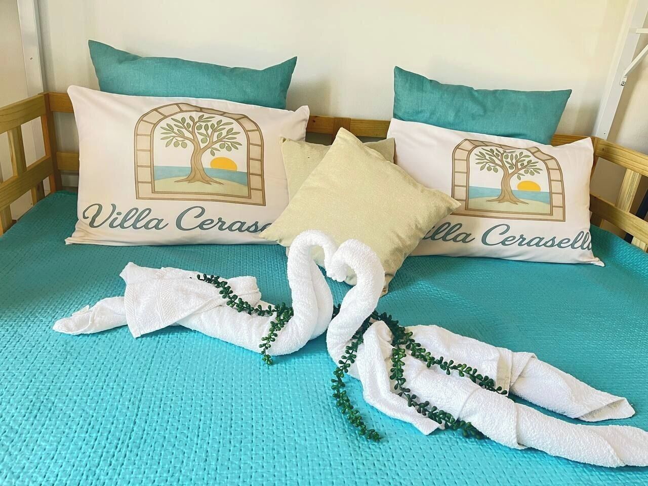 A bed with two pillows, each featuring a tree and the text 'Villa Ceras.'