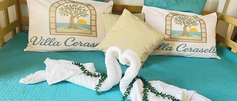 A bed with two pillows, each featuring a tree and the text 'Villa Ceras.'