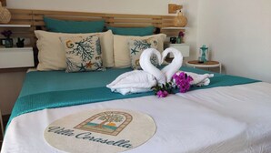 Una cama bien hecha con una escultura de cisne hecha con toallas, ropa de cama color turquesa y un logotipo bordado circular.