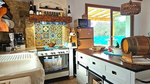 Una cocina con pared de piedra, salpicadero de azulejos, techo de madera y ventana con vistas.