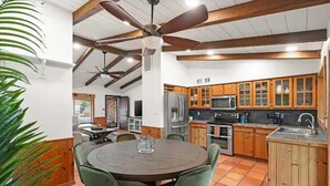 A spacious kitchen with wooden cabinets, a central island, and a dining area with green chairs. - Chandler Southwest Gem w/Private Backyard Retreat! (Chandler)