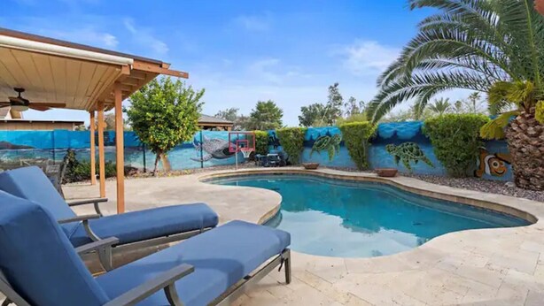 A swimming pool with lounge chairs, a covered seating area, and a mural with sea creatures. - Chandler Southwest Gem w/Private Backyard Retreat! (Chandler)
